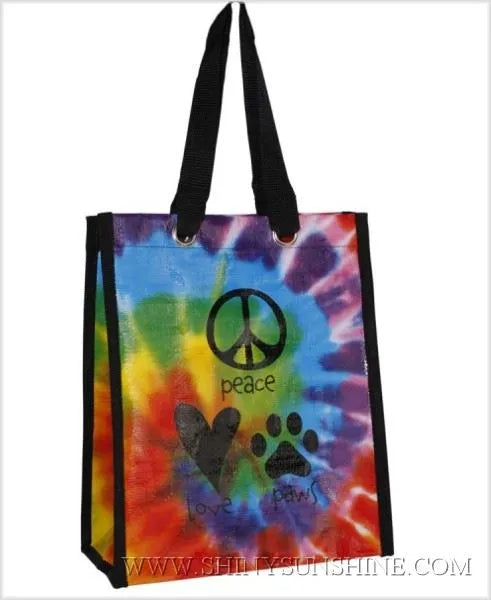 Tie-dye tote bag with peace symbol, heart, and paw print design on a white background.